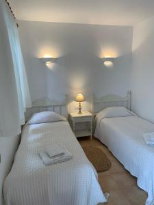 two beds in a room with two tables and two lamps at Es Cucó in Cala Galdana