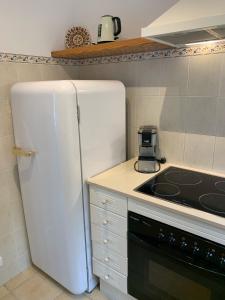 a kitchen with a white refrigerator and a stove at Es Cucó in Cala Galdana