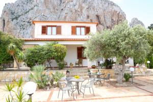a house with a table and chairs in front of a mountain at Villa Benny in San Vito lo Capo