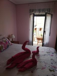 2 toallas rojas en una cama con ventana en Casa Rural Pilarraña, en Ujué