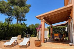 een patio met witte stoelen en een houten pergola bij Casa Mar Blau - mediterranean house in Puigderrós