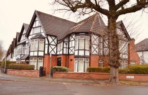 una casa bianca e nera con un albero davanti di Abbeyfield Guesthouse a Liverpool