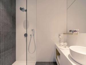 baño blanco con ducha y lavamanos en Mercure Roeselare, en Roeselare