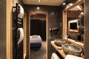 a bathroom with two sinks and a room with a bed at Le Domaine des Prés Verts Suites & Chambres avec Jacuzzi Privatif à Châteauneuf in Châteauneuf