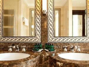 a bathroom with two sinks and a mirror at Royal Hotel Oran - MGallery Hotel Collection in Oran