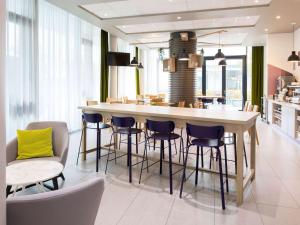a kitchen with a bar with stools and a table at Aparthotel Adagio access München City Olympiapark in Munich