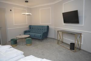 een woonkamer met een blauwe bank en een tv bij Atmosfera Apartament 3 in Bytów
