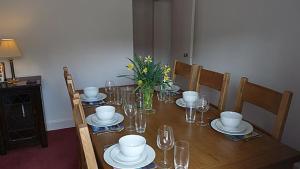 una mesa de madera con platos y vasos. en Keeper's Cottage en Lochgilphead