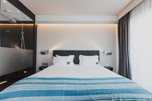 a bedroom with a large white bed with blue stripes at H Boutique Peña Parda in La Herradura