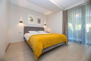a bedroom with a large bed with a yellow blanket at Cuprum Poilsis in Palanga