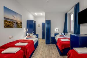 a bedroom with two beds with red and blue sheets at Koje Hostel in Hamburg
