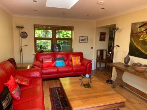 a living room with a red leather couch and a table at Abbey Cottage, Findhorn in Findhorn