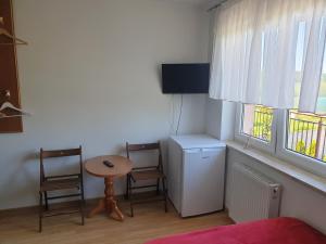 a room with a table and two chairs and a small table and two windows at POKOJE U MIKOŁAJA in Kamień Pomorski