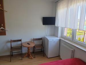 een kamer met een tafel en twee stoelen en een kleine tafel en twee ramen bij POKOJE U MIKOŁAJA in Kamień Pomorski