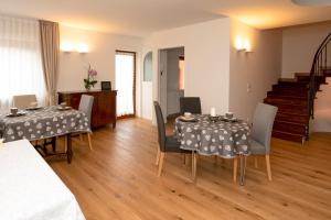 a living room with two tables and chairs and a staircase at Larici Rooms in Roana