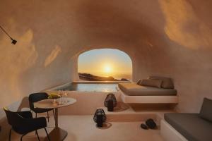 Divine Cave Experience في إيميروفيغلي: غرفة بسرير وطاولة وغروب الشمس