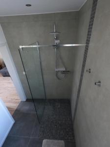 a shower with a glass door in a bathroom at Ferienwohnung Südkurve in Briedel +25 photos