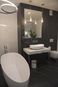 La salle de bains est pourvue d'une baignoire blanche, d'un lavabo et d'un miroir. dans l'établissement Atmosfera Apartament 4, à Bytów