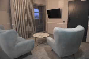uma sala de estar com duas cadeiras e uma televisão em Atmosfera Apartament 4 em Bytów