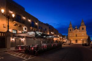 a building with an umbrella on a street at night at Lure Hotel & Spa - Adults Only in Mellieħa