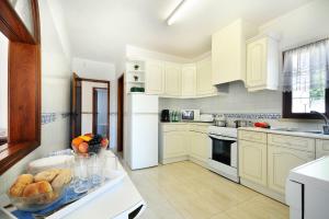 - une cuisine avec des placards blancs et un bol de fruits sur un comptoir dans l'établissement Villa Medeira by Villa Plus, à Albufeira