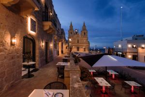 an outdoor restaurant with tables and an umbrella at Lure Hotel & Spa - Adults Only in Mellieħa