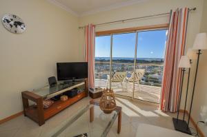 a living room with a tv and a large window at Encosta da Orada by OCvillas in Albufeira