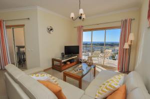 ein Wohnzimmer mit einem weißen Sofa und einem Fernseher in der Unterkunft Encosta da Orada by OCvillas in Albufeira