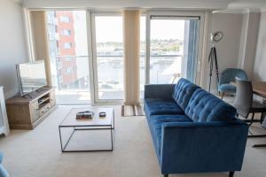 a living room with a blue couch and a table at Toothbrush Apartments - Ipswich Waterfront - Anchor St in Ipswich