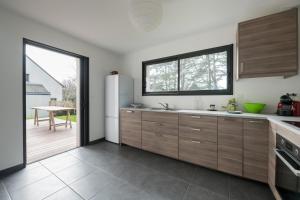 a kitchen with wooden cabinets and a large window at Une belle maison ouverte sur le jardin, près de la mer in Piriac-sur-Mer