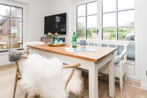 a dining room with a table and two white chairs at Hüs gur seen in Rantum