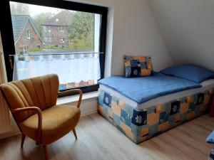 a bedroom with a bed and a chair and a window at Haus Edel in Wesselburen