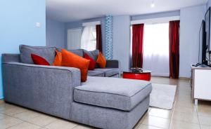 a living room with a gray couch and orange pillows at Martha's cozy home near JKIA airport in Nairobi