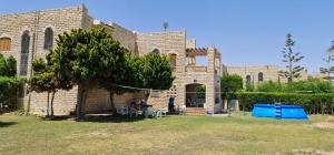 a large brick building with a yard in front of it at Big Chalet with Pool & Garden at Marina 4 in El Alamein