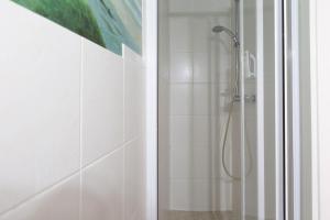 a shower stall in a bathroom with white tiles at Muschel 2 in Ahrenshoop