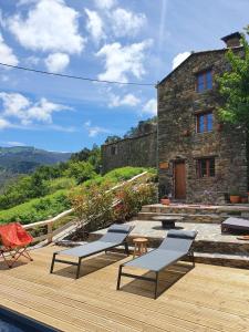 eine Holzterrasse mit Stühlen und ein Gebäude in der Unterkunft Casa do Ti Tóte in Talasnal