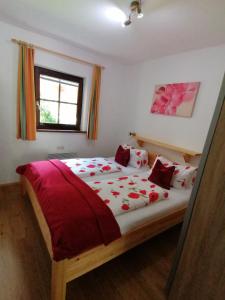 a bedroom with a large bed with red sheets and a window at Gondelblick in Alpbach