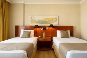 um quarto de hotel com duas camas e uma mesa em Pineapples BPremium - Excelentes suítes no Rio de Janeiro