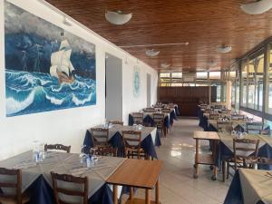 Caravella في ديفا مارينا: غرفة طعام بها طاولات وكراسي و لوحة على الحائط