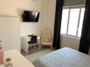 a bedroom with a bed and a desk and a television at Nonna Febronia in Patti