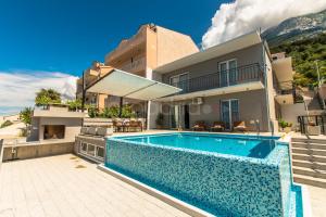een villa met een zwembad en een huis bij Apartment Stanley with Private Pool in Makarska
