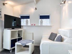 sala de estar con sofá blanco y TV de pantalla plana en Knusse vakantiewoning Domburg DO04, en Domburg