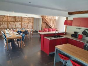una cucina e una sala da pranzo con armadi rossi e tavoli di Le Gîte des Globe-Trotters pour 15 pers a Commenailles