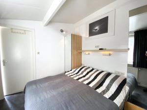 1 dormitorio con 1 cama y TV en la pared en Knusse vakantiewoning Domburg DO04, en Domburg