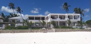 a white house on the beach with palm trees at La Villa de Victor Kigomani in Matemwe