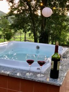 a bottle of wine and two wine glasses sitting next to a tub at Chalé Suíço - Chalés Belo Monte - Sítio Belo Monte in Pacoti