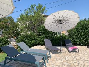 a group of chairs and an umbrella on a patio at Apartments Ban in Novi Vinodolski