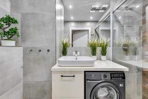 a bathroom with a sink and a washing machine at Dom & House - Apartments Waterlane Island in Gdańsk