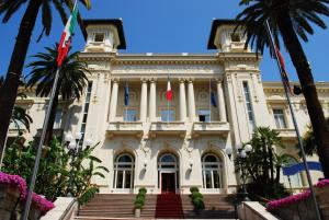 un bâtiment avec des drapeaux et des palmiers devant lui dans l'établissement Via Mameli 5, à Sanremo