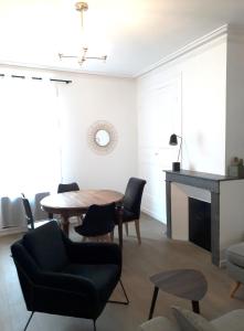 een woonkamer met een tafel en stoelen en een open haard bij MIRA BELLA - Centre ville avec jardin in Saumur